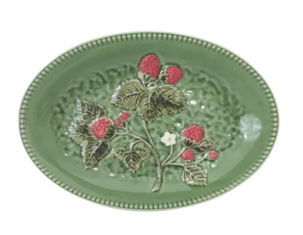 An oval green ceramic plate featuring a raised relief design of a strawberry plant with red berries and green leaves, set against a plain white background.