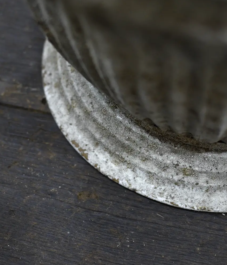 Close detail of ribbed body and weathered patina texture on fluted metal planter