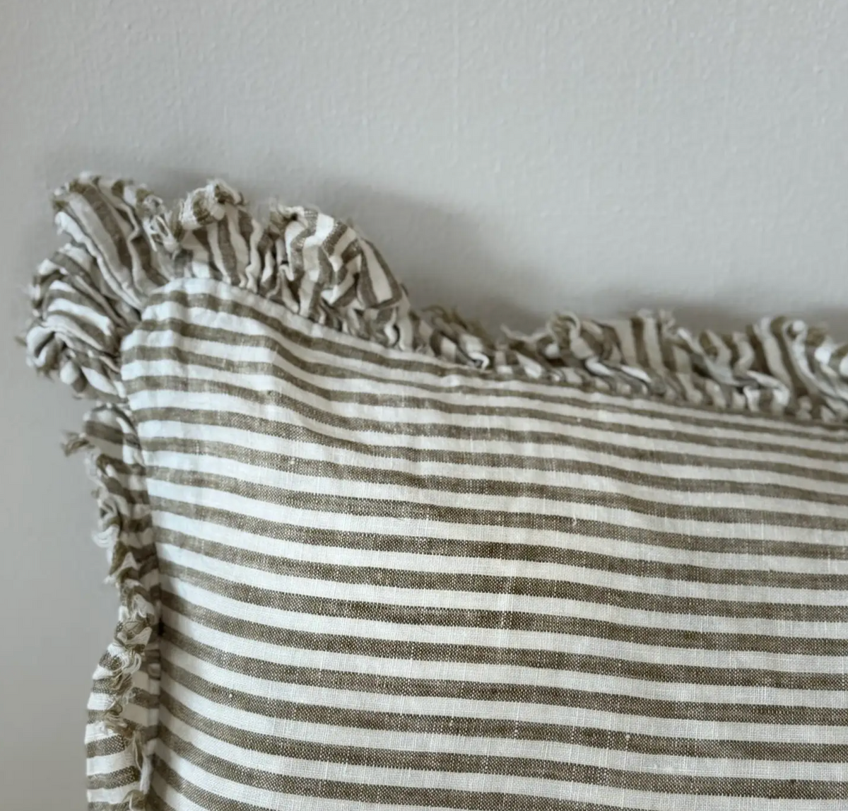 Close-up of the olive striped linen fabric and ruffled edge on a bolster cushion cover