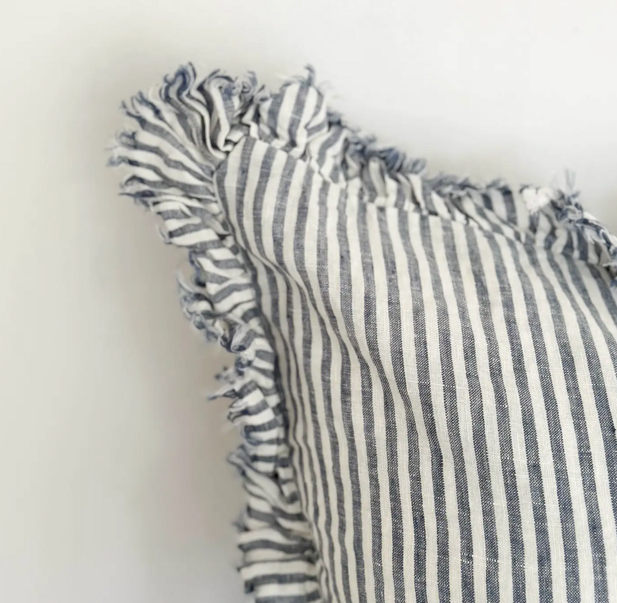 Close-up of blue and cream striped linen fabric and ruffled edge on a cushion