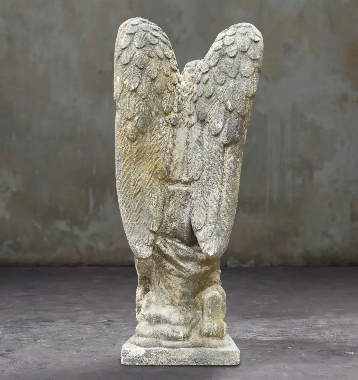 Rear view of the kneeling angel statue showing both feathered wings