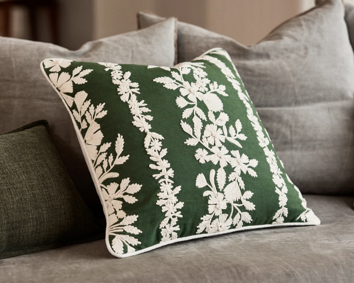 Green and cream botanical trellis cushion styled on a grey sofa