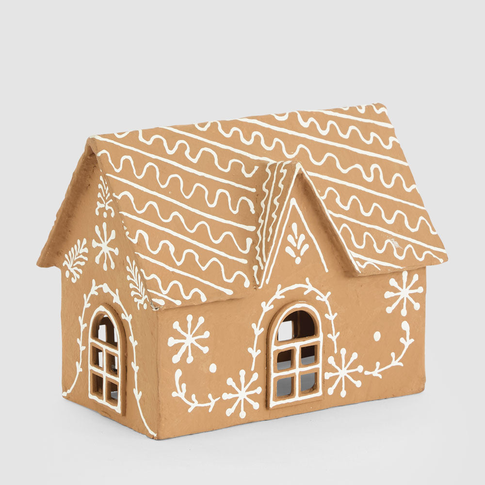 Rear view of the gingerbread cottage showing white snowflakes, leafy lines and an arched window
