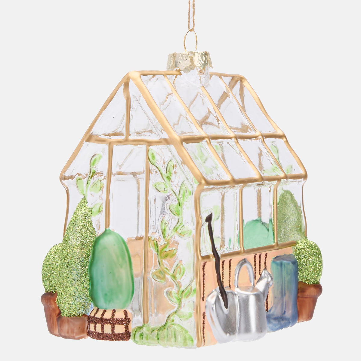 Angled view of the glass greenhouse decoration showing gardening tools and glittered green plants