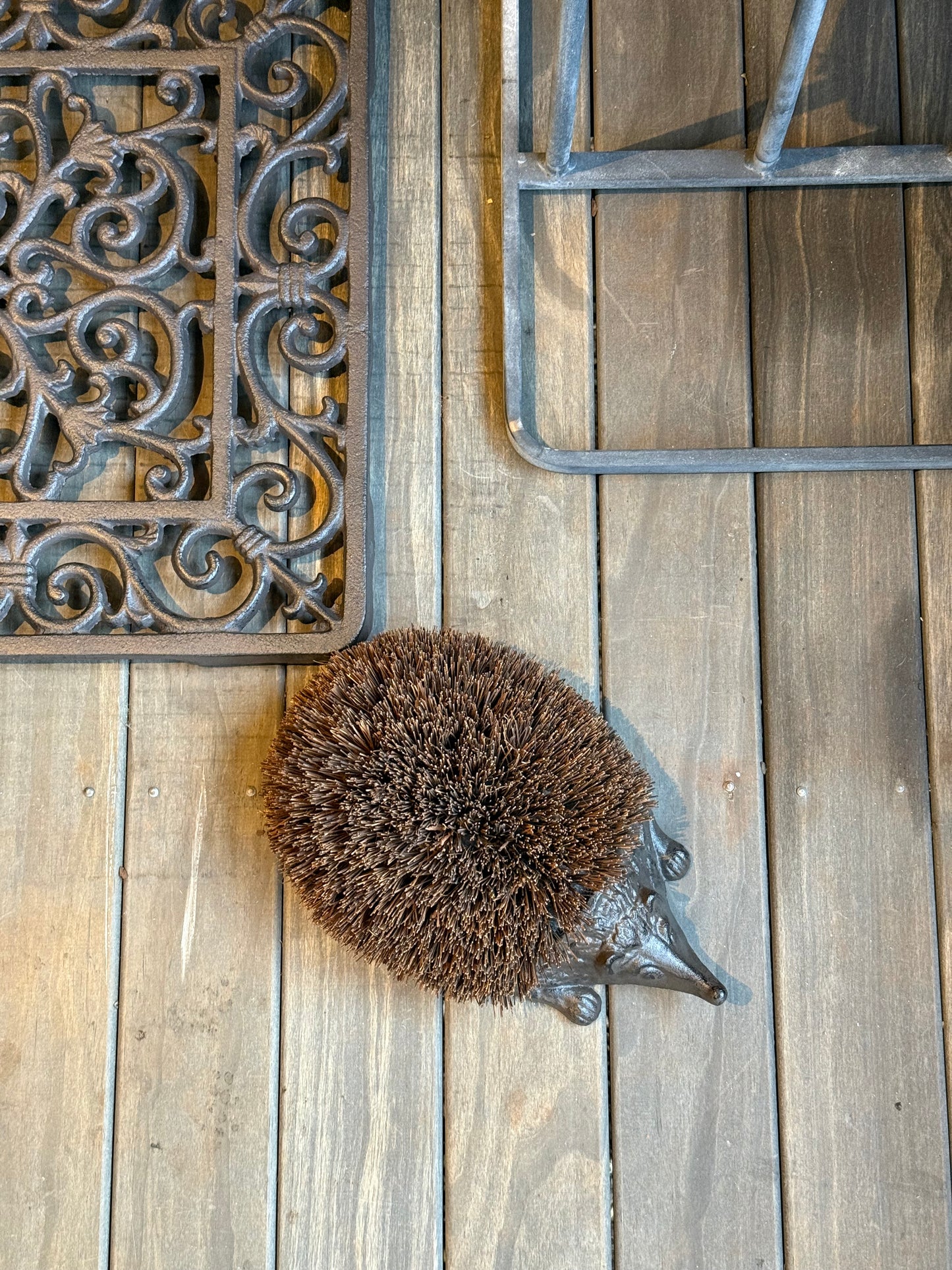 Cast Iron Hedgehog Boot Brush with coir back - top view on timber deck alongside cast iron door mat