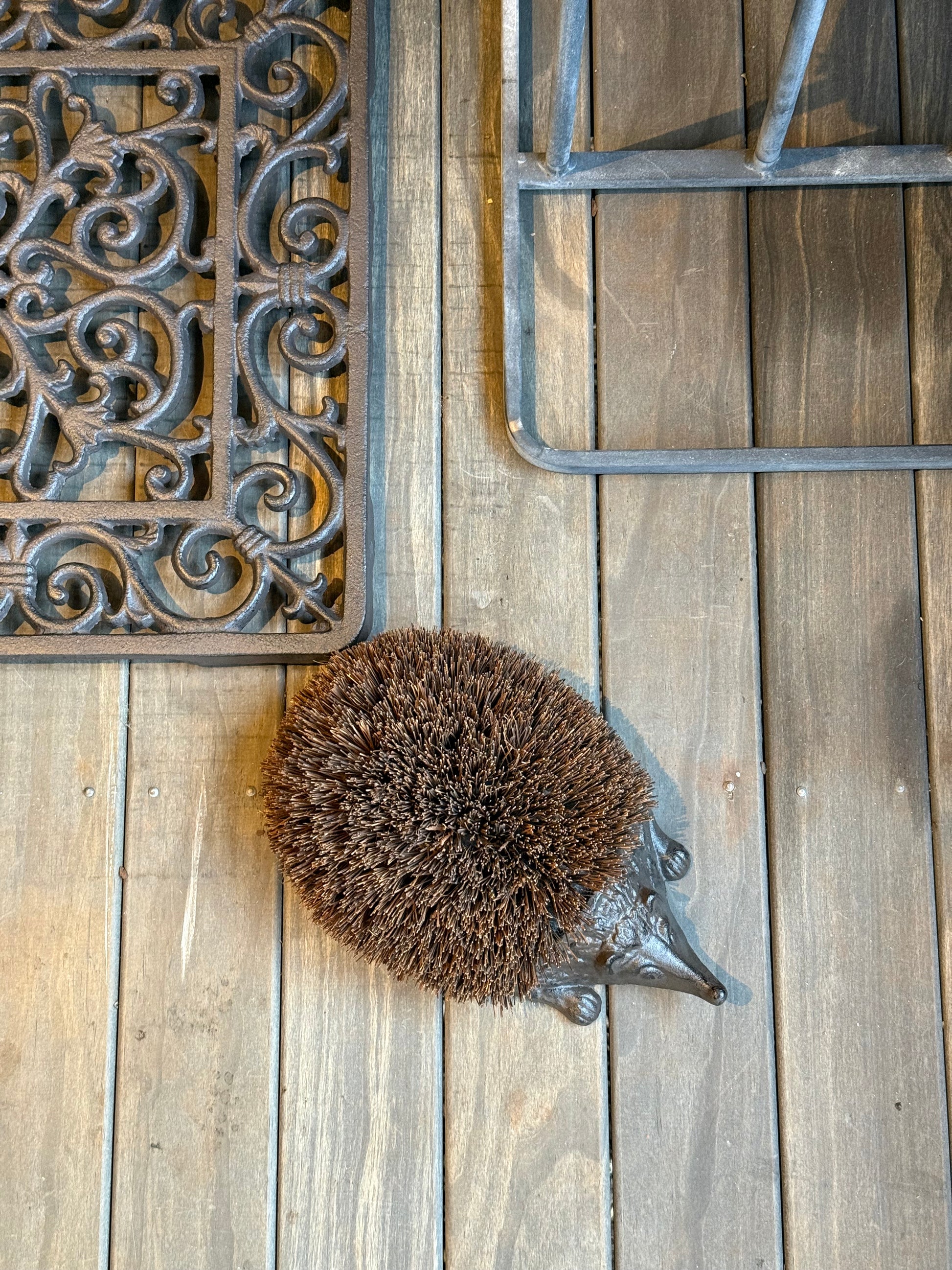 Cast Iron Hedgehog Boot Brush with coir back - top view on timber deck alongside cast iron door mat