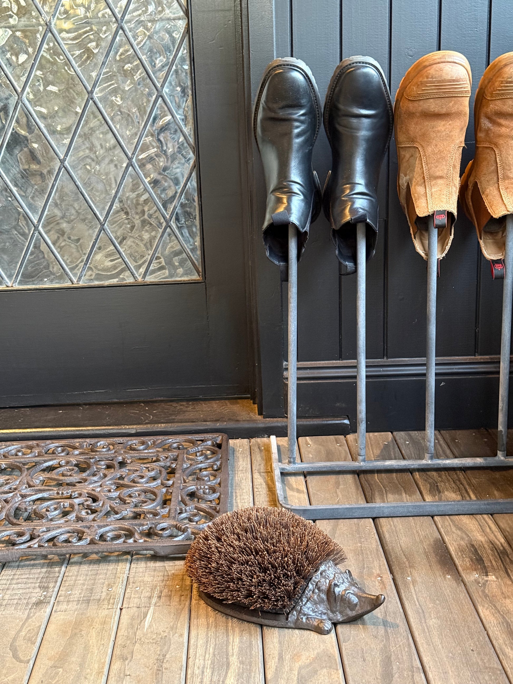 Cast Iron Hedgehog Boot Brush in use at front entry with boots and cast iron door mat