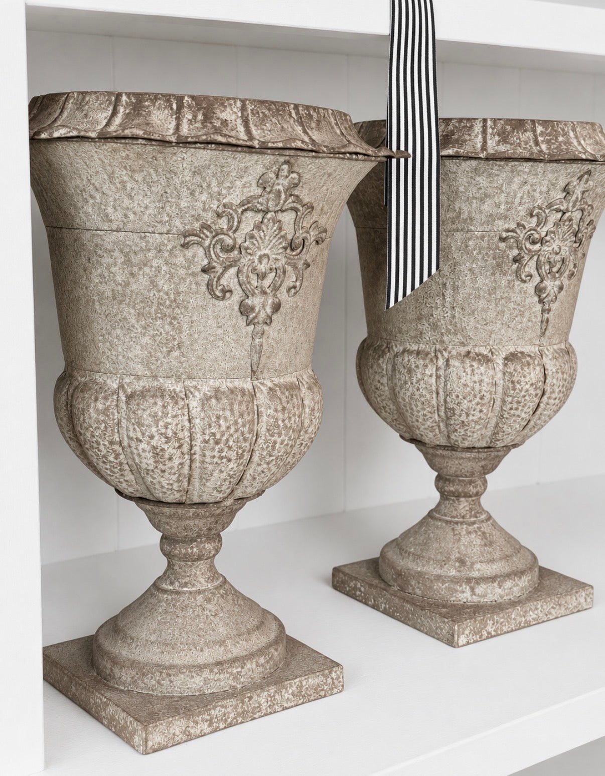 Pair of motif patina metal urns styled on shelf - HAROLDS