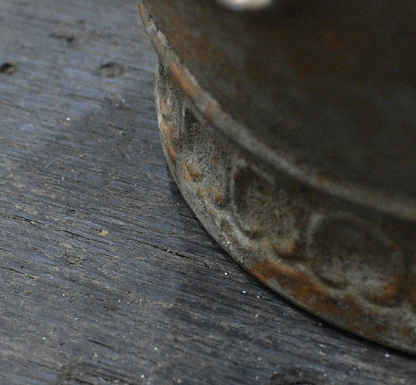 Close detail of embossed scrollwork band and aged patina on metal crown dish base