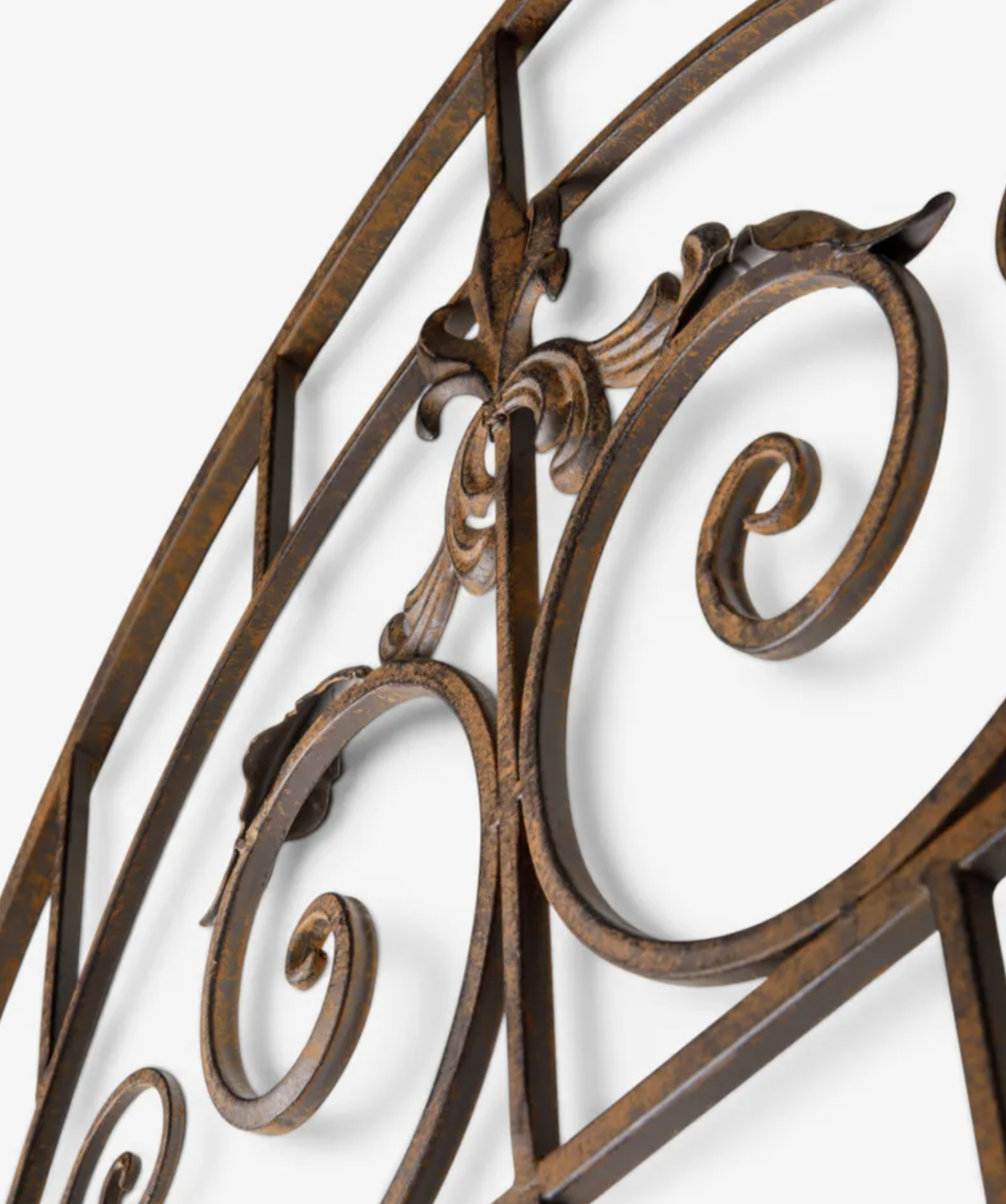 Close-up of an ornate metal wall decor piece with scrolled and curved ironwork in a distressed bronze finish against a plain white background.
