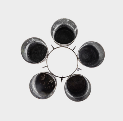 Five dark, used plastic cups arranged in a circular pattern on a light gray background.