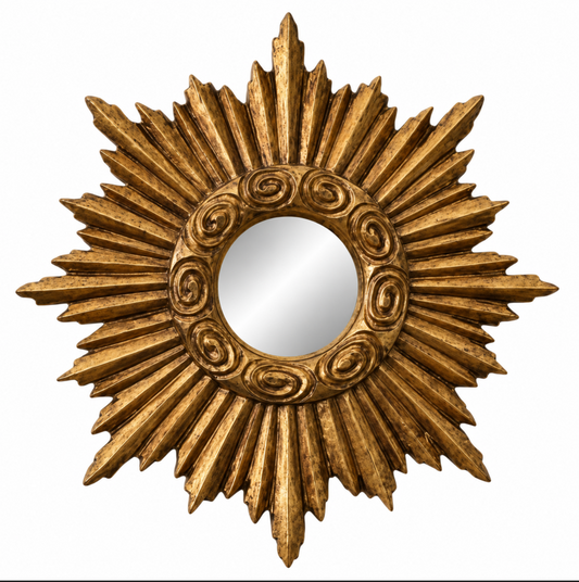A gold sunburst wall mirror with ornate carved details around the circular reflective center, shown against a plain white background.