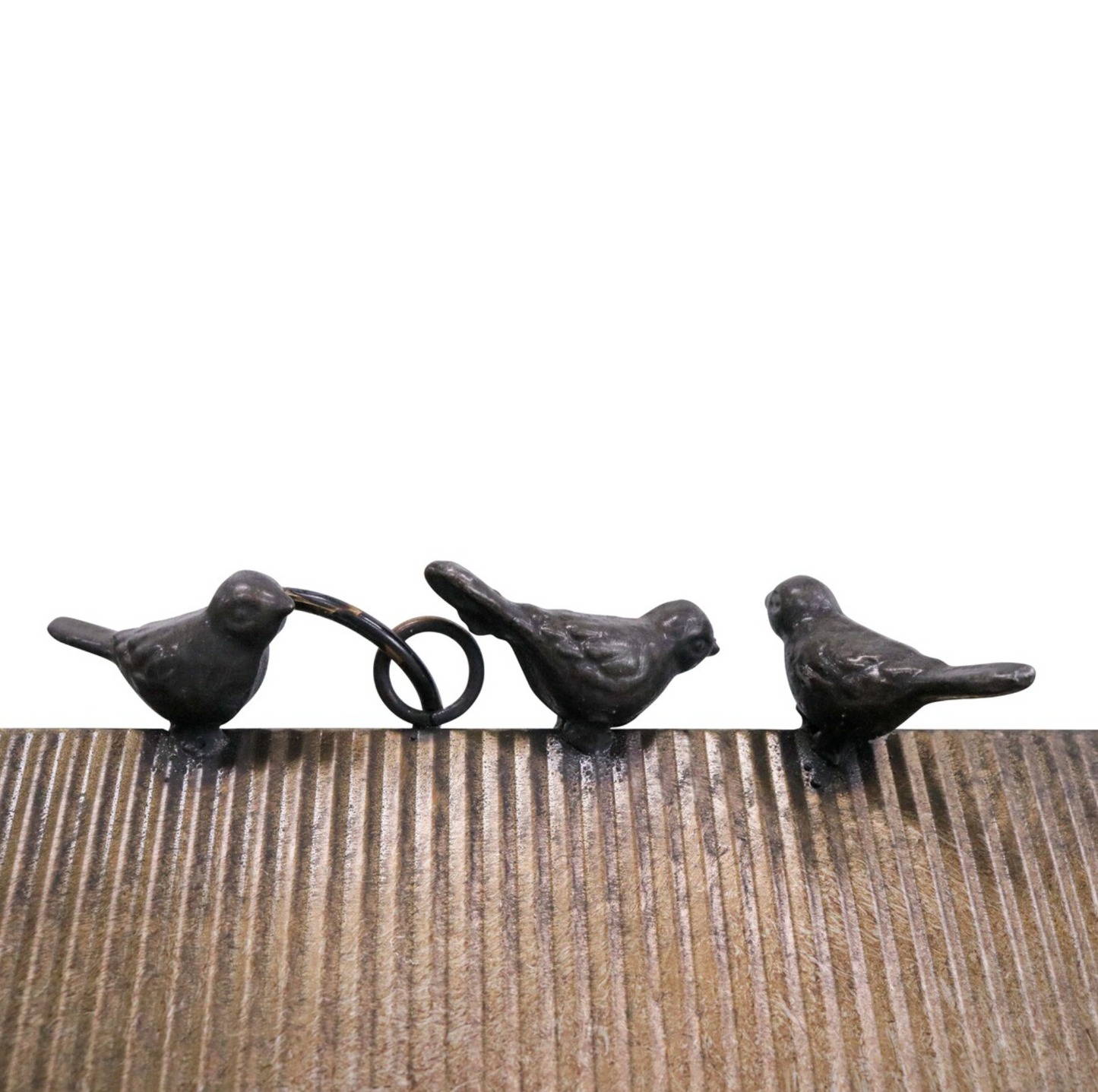 Three small cast iron bird ornaments in dark weathered finish perched on a wooden surface