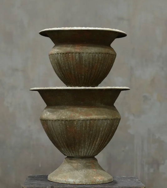 Two fluted urns in Oxido finish stacked showing Medium and Large size comparison with dark weathered patina