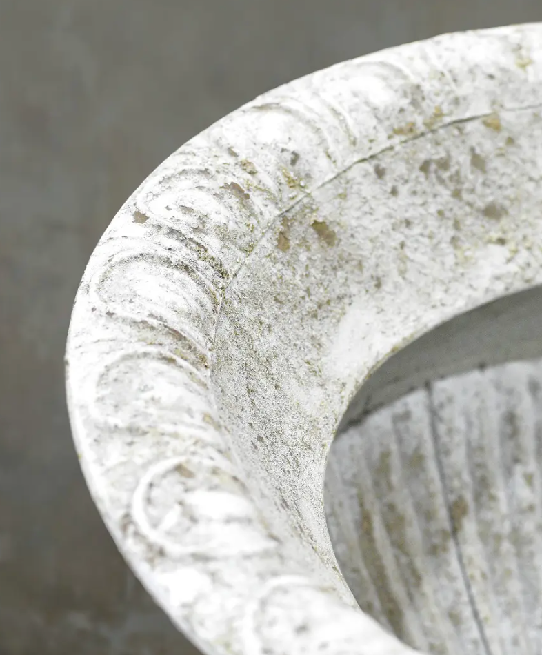 Close detail of beaded rim and weathered white patina on fluted urn