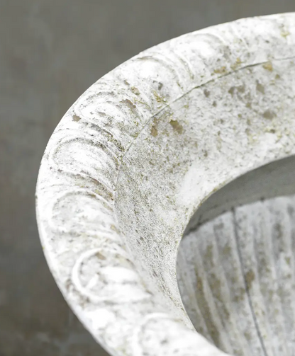 Close detail of beaded rim and weathered white patina on fluted urn