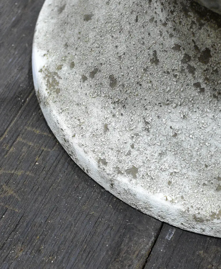 Close detail of pitted stone-like base texture on fluted urn in aged white patina