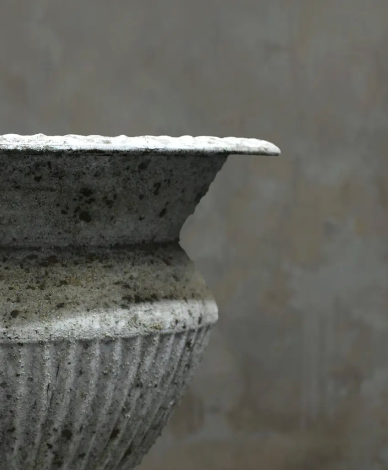 Close detail of vertically fluted body and beaded rim on fluted urn showing patina depth