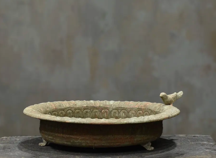 Cast iron bird dish in darker aged patina showing perched bird and scalloped rim detail