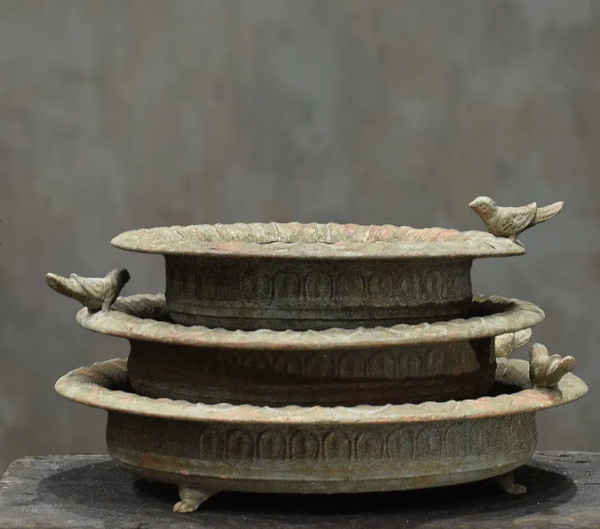 Close detail of scalloped rim and embossed arch band on cast iron bird dish in aged white patina