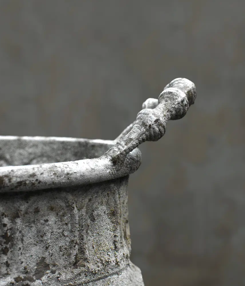Close detail of repeating foliate panels on embossed trough planter in aged white patina