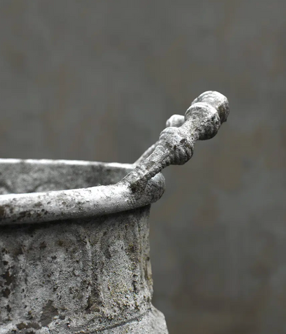 Close detail of repeating foliate panels on embossed trough planter in aged white patina