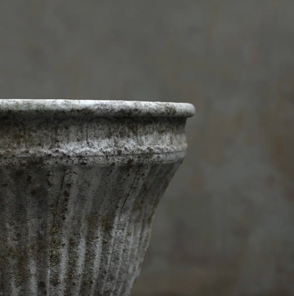 Close detail of scrollwork band below rim on fluted planter in aged white patina showing pitted texture