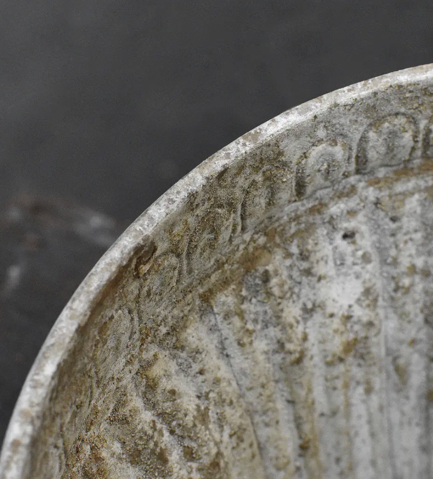 Close detail of flat circular foot base on fluted planter showing aged stone-like patina