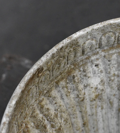 Close detail of flat circular foot base on fluted planter showing aged stone-like patina