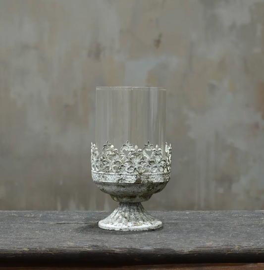 Small footed metal crown candle holder with pierced fleur-de-lis band and glass hurricane insert in aged Blanca patina