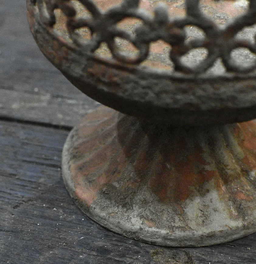 Close detail of ribbed pedestal foot base on metal crown candle holder showing aged patina texture