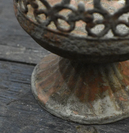 Close detail of ribbed pedestal foot base on metal crown candle holder showing aged patina texture
