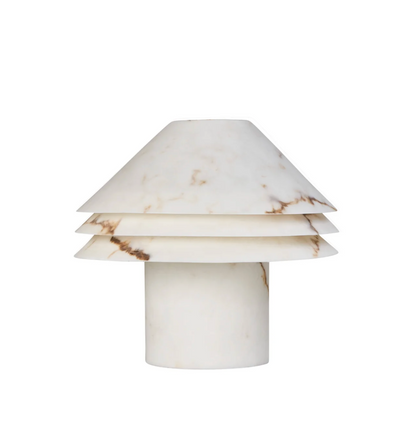 Faux alabaster tiered table lamp lit, warm glow emanating between stacked conical disc shades