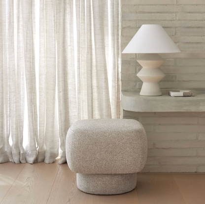 Geometric table lamp styled beside a boucle ottoman in a light-filled room