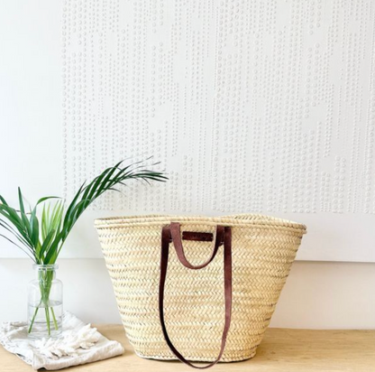 Tan palm leaf market basket styled in a home