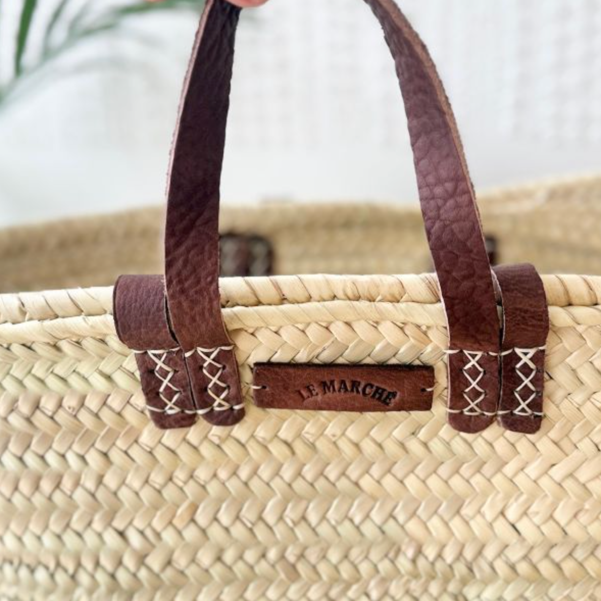Detail of palm leaf weave and leather handles on tan market basket