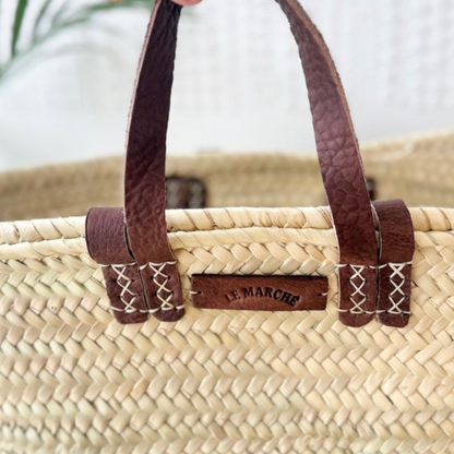 Detail of palm leaf weave and leather handles on tan market basket