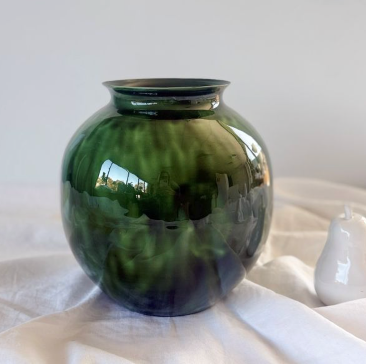Glossy green decorative vase styled on a table