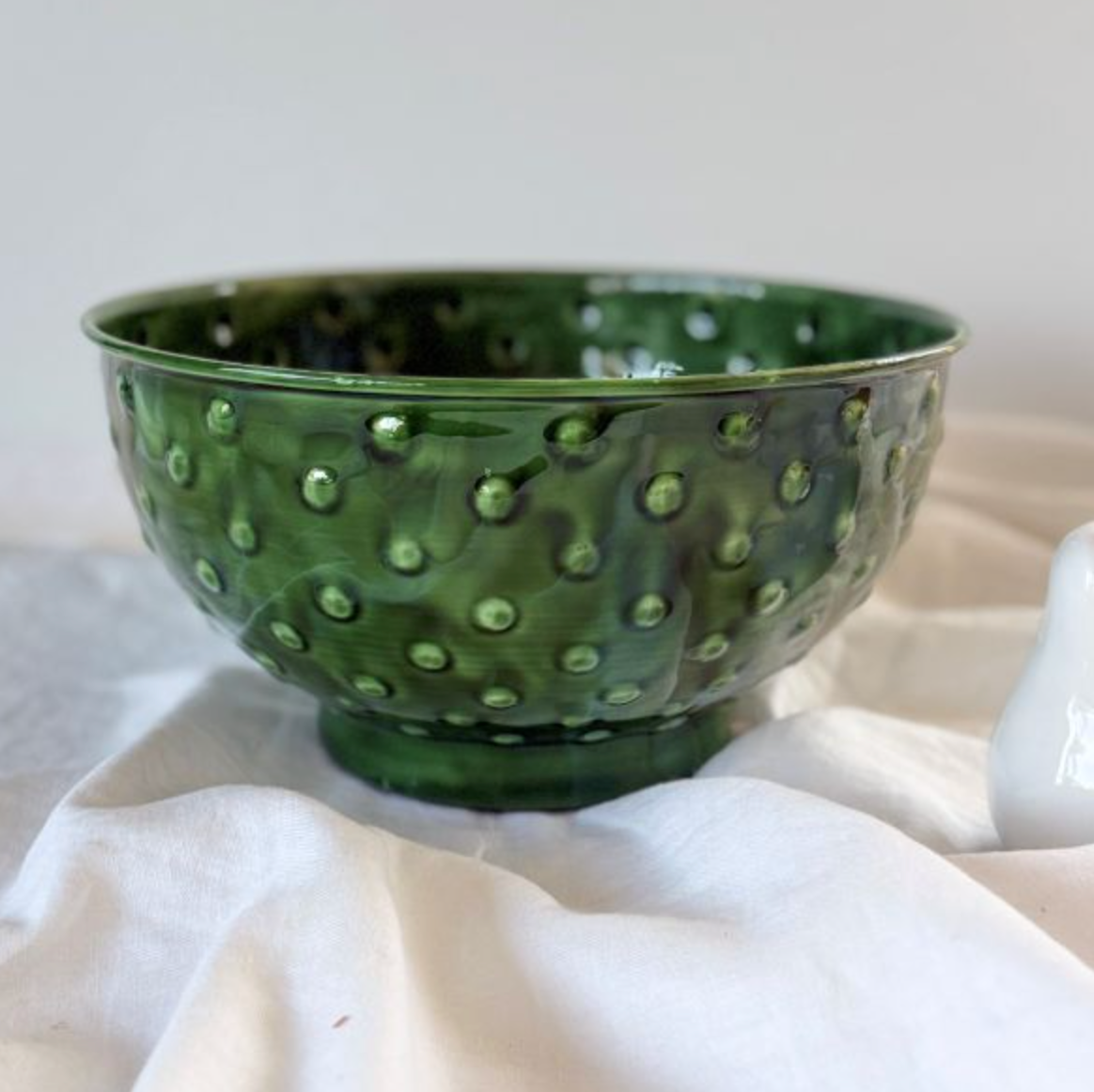 Green enamel bowl with raised spots and a footed base