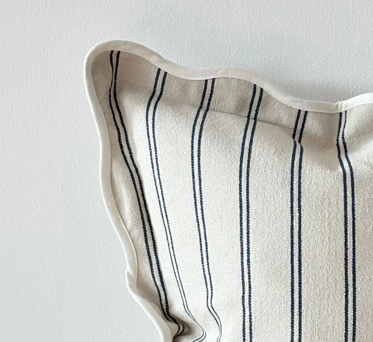 Close-up of navy and cream striped fabric and scalloped edge on a cushion cover