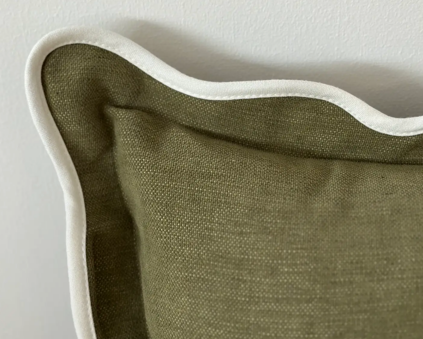 Close-up of the olive textured fabric and scalloped edge on a bolster cushion cover
