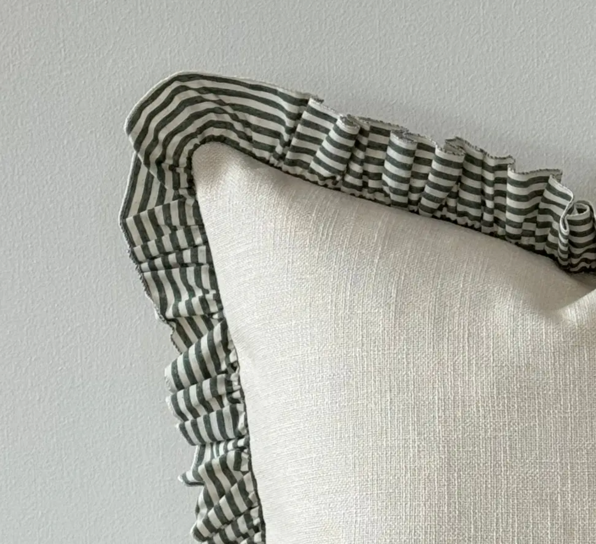 Close-up of the green and cream striped ruffle edge and textured cushion cover