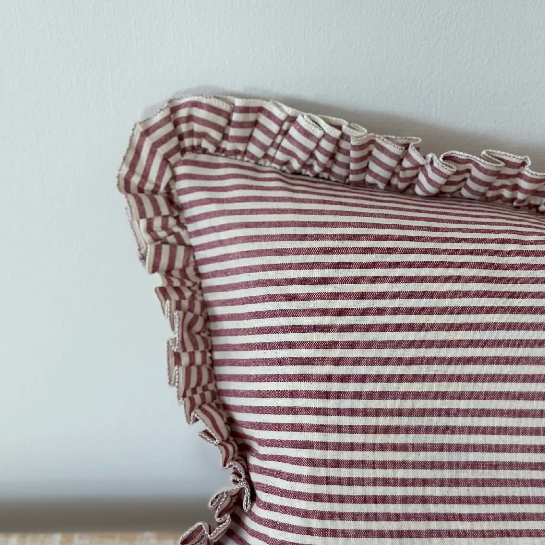 Close-up of the burgundy striped fabric and ruffled edge on a rectangular cushion cover