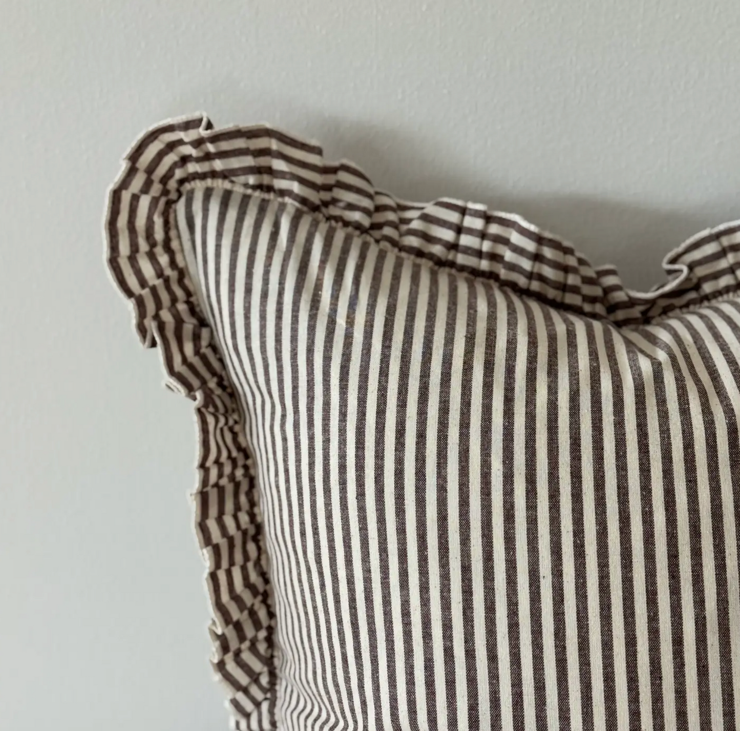 Close-up of the dark brown striped fabric and ruffled edge on a rectangular cushion cover