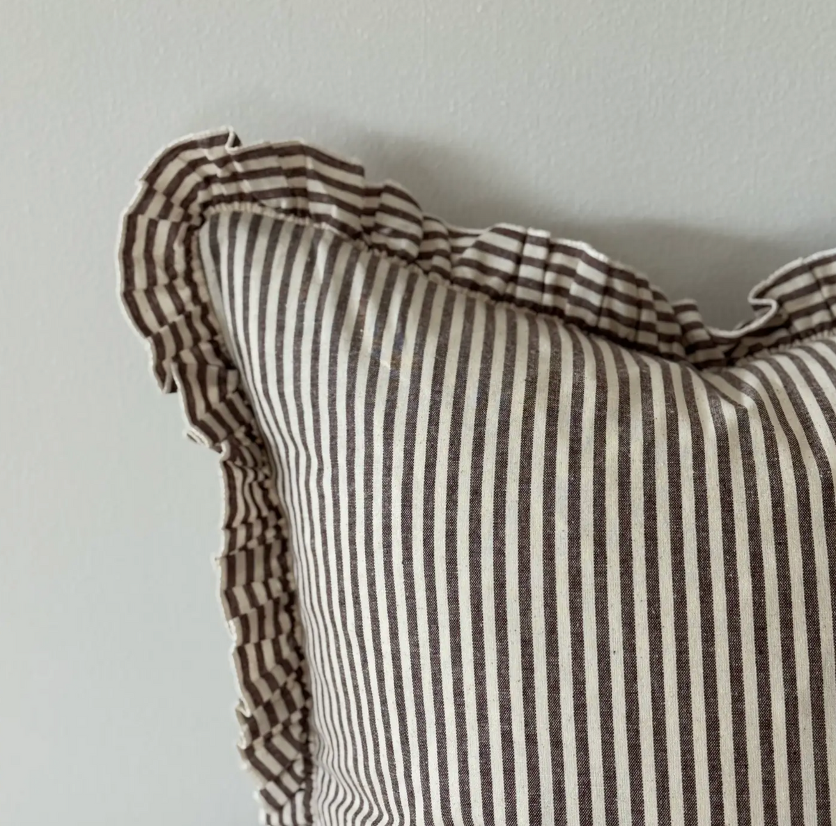Close-up of the dark brown striped fabric and ruffled edge on a rectangular cushion cover