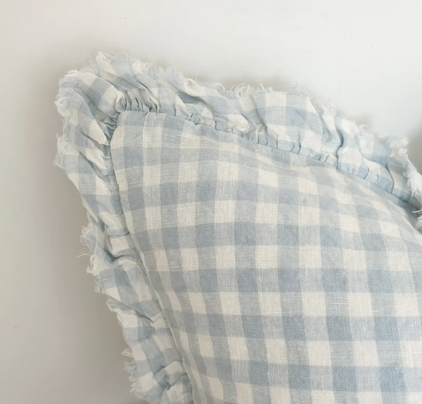 Square blue and cream gingham cushion cover with a ruffled edge on a white background