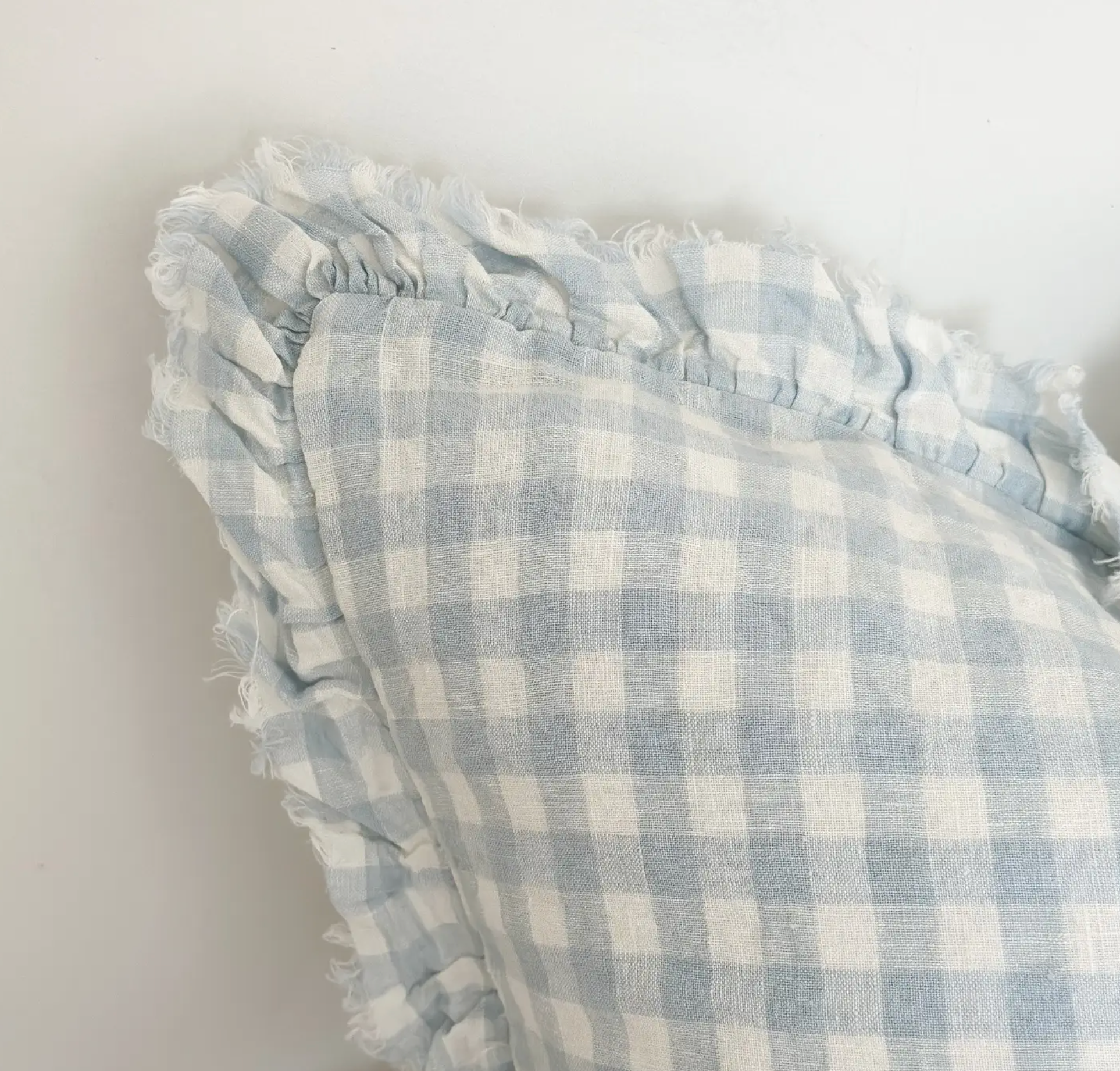 Square blue and cream gingham cushion cover with a ruffled edge on a white background