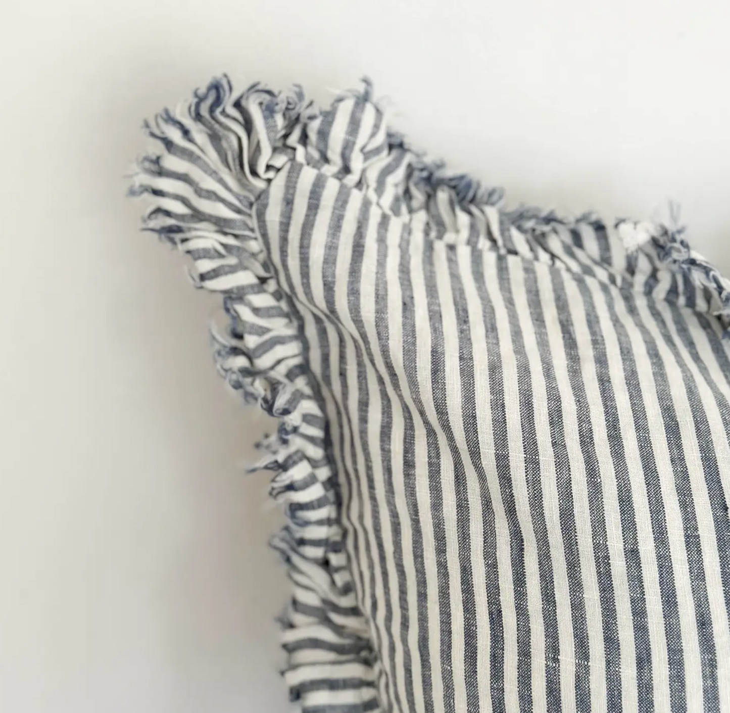 Close-up of blue and cream striped linen fabric and ruffled edge on a cushion