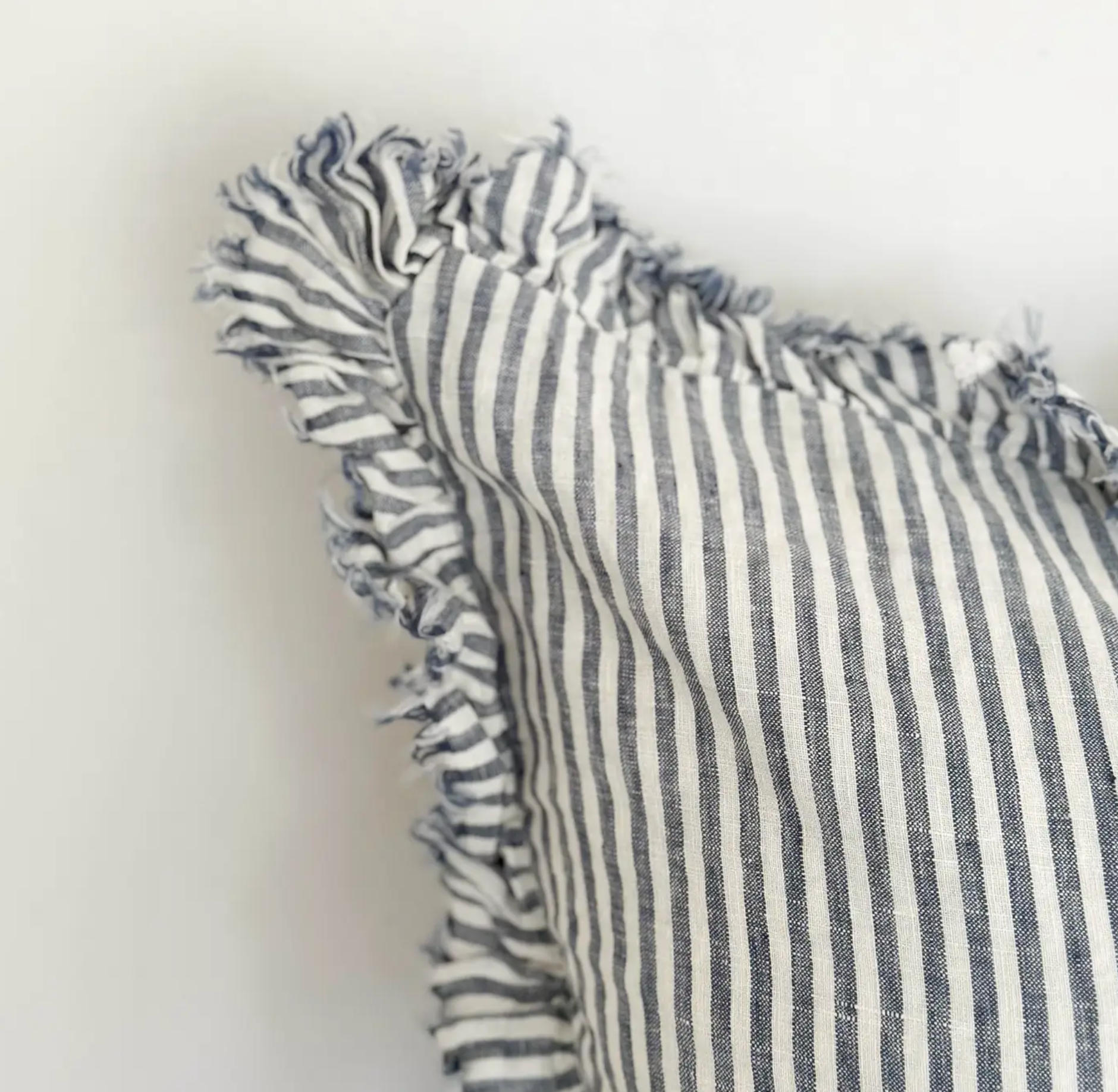 Close-up of blue and cream striped linen fabric and ruffled edge on a cushion
