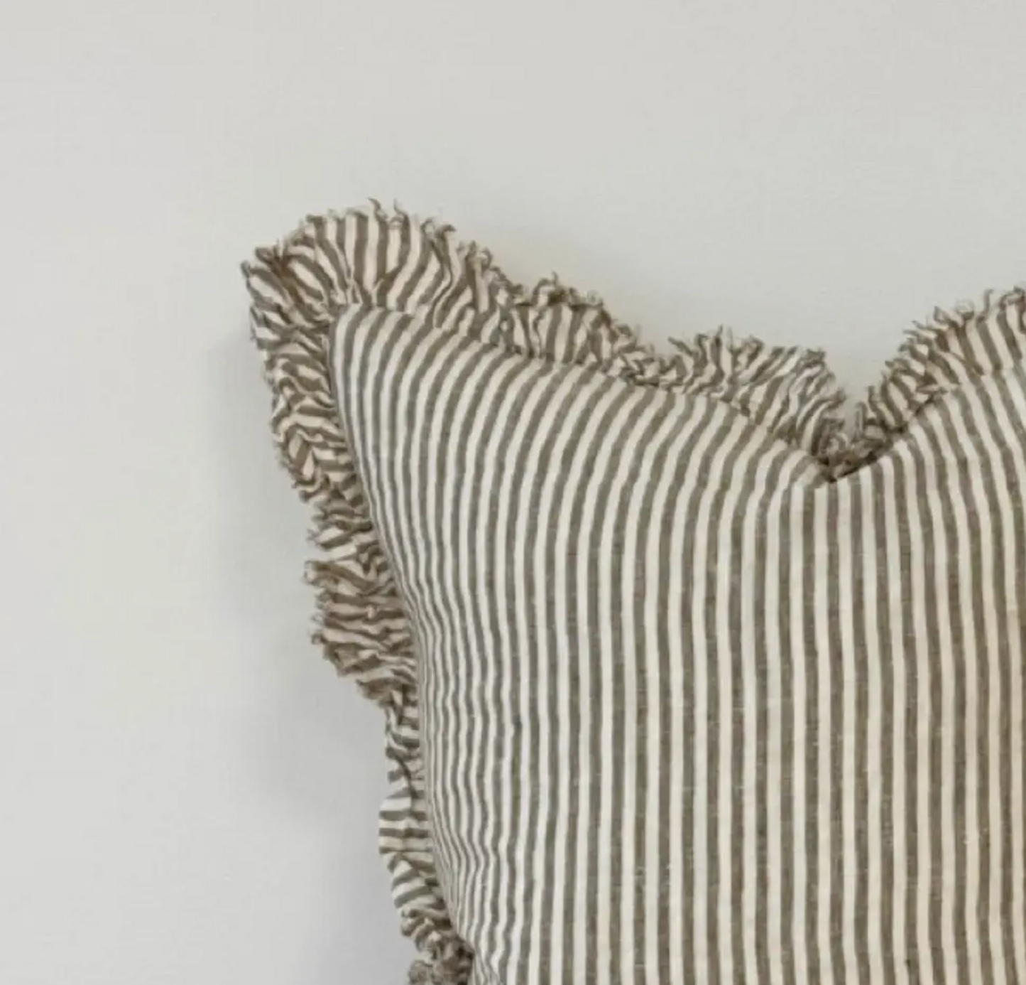 Close-up of olive striped linen fabric and ruffled edge on a cushion